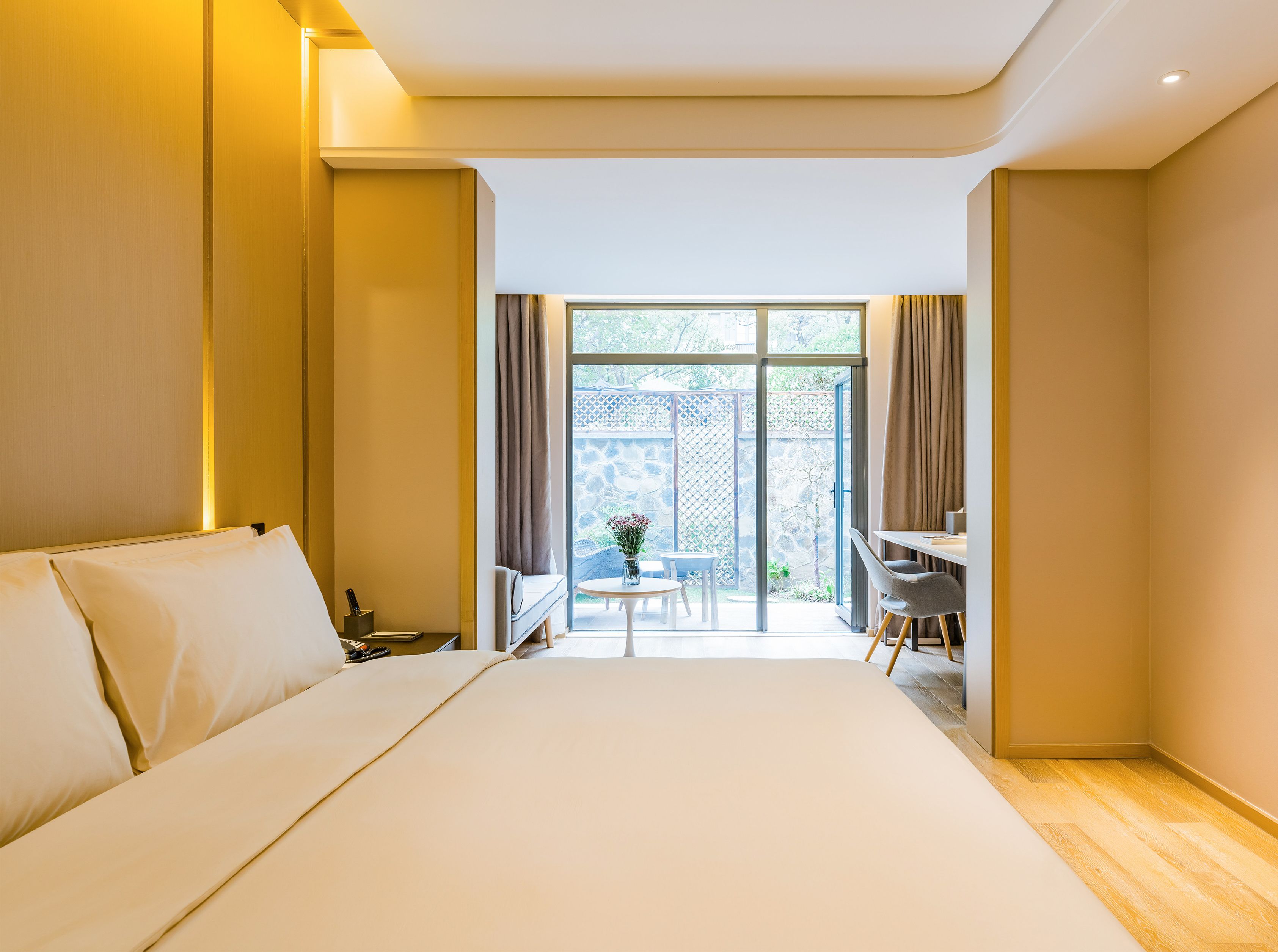A hotel room with a large bed, a desk, and a view of the outdoors.