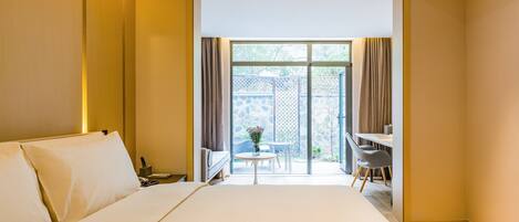 A hotel room with a large bed, a desk, and a view of the outdoors.