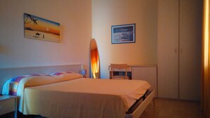 A bedroom with a bed, a nightstand, a desk, a chair, a wardrobe, and two wall-mounted paintings. - Sybaris B&B (Cassano allo Ionio)