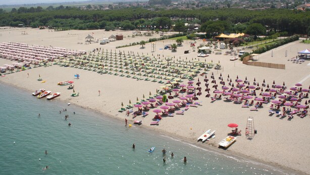 A beach with rows of umbrellas and sun loungers, a sandy shore, and boats in the water. - Sybaris B&B (Cassano allo Ionio)