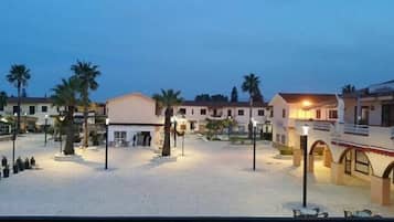 Cortile di un hotel con diversi edifici, palme e una galleria coperta.