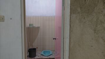A small bathroom with a toilet, a trash bin, and a blue bidet.