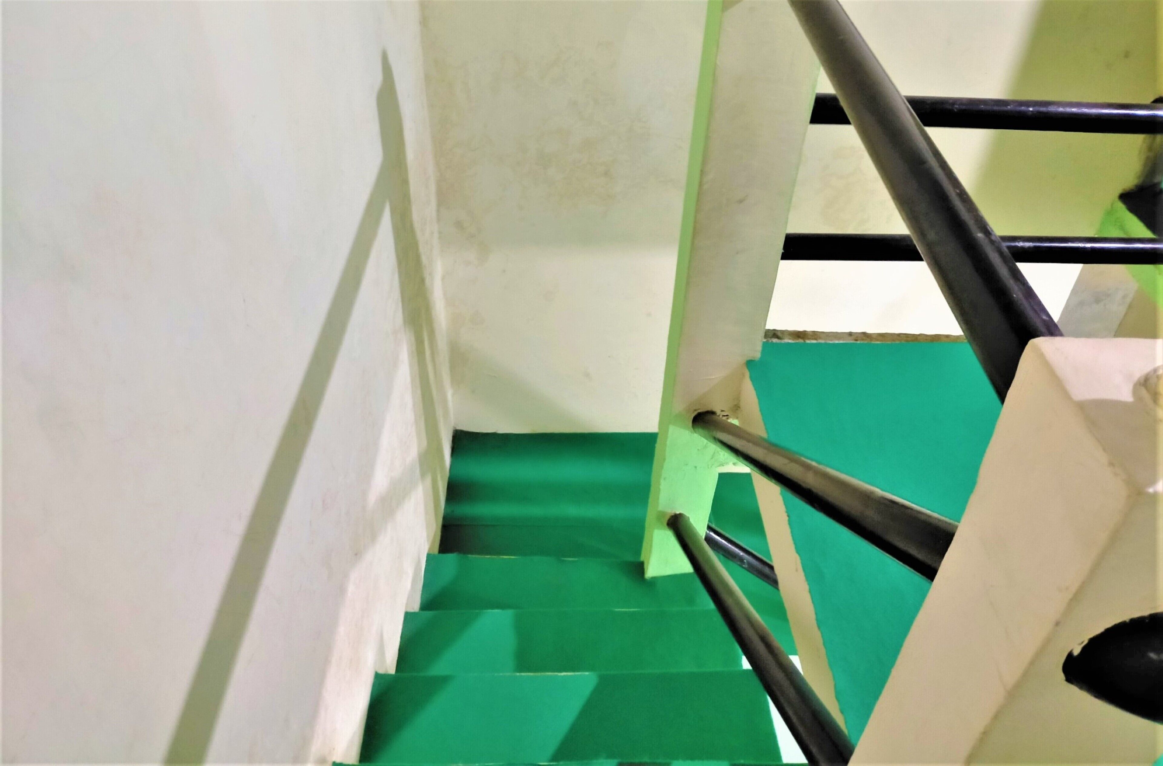 A staircase with green steps and a handrail.