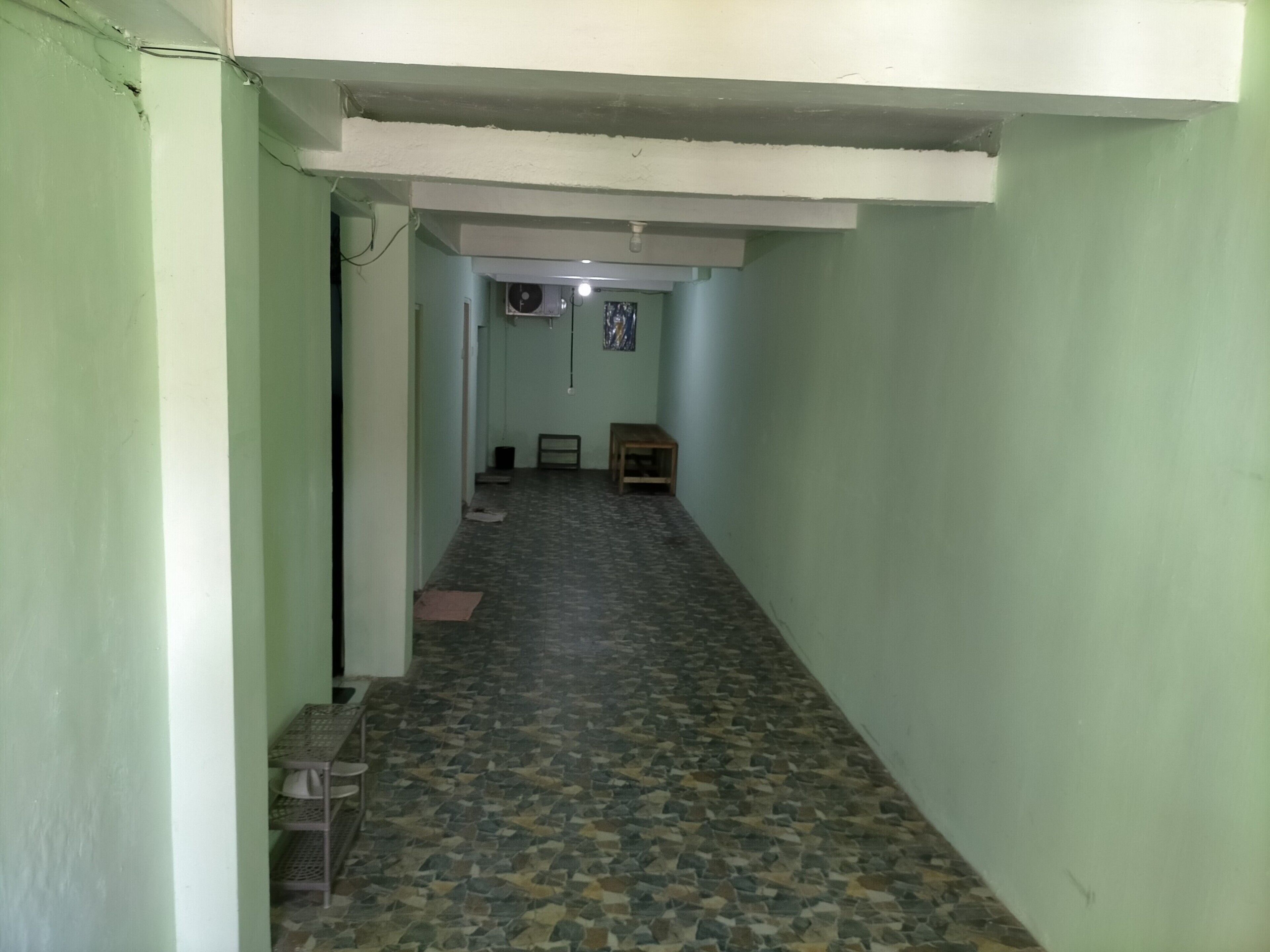 A narrow hallway with a tiled floor, a bench, and a small table.