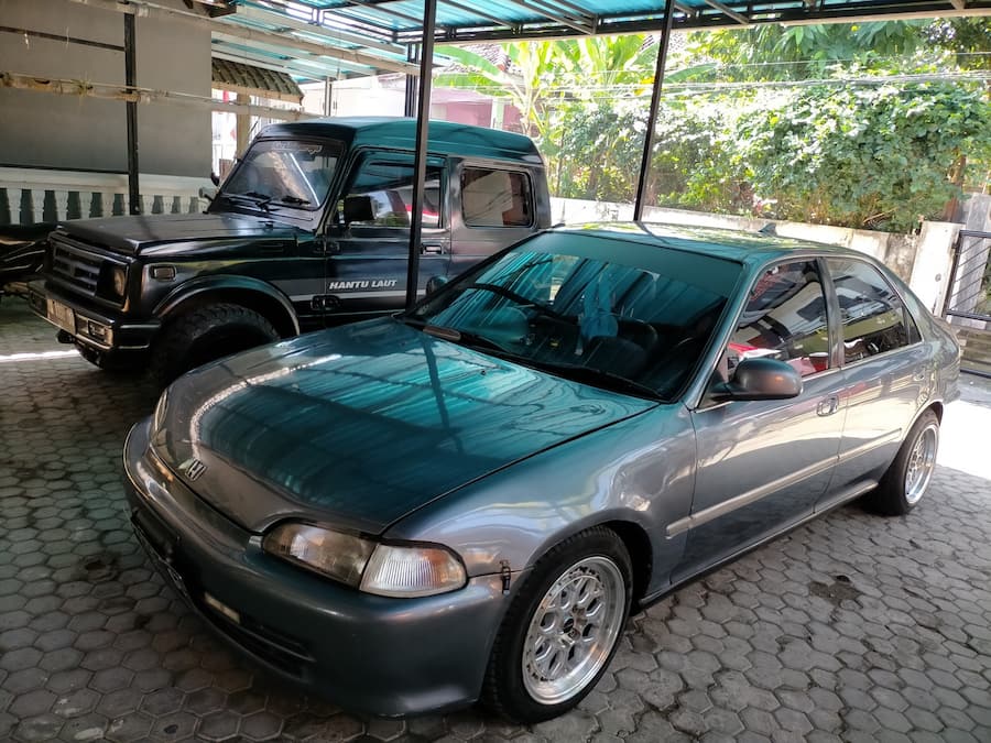 A car parked in a covered parking area with a tiled floor.