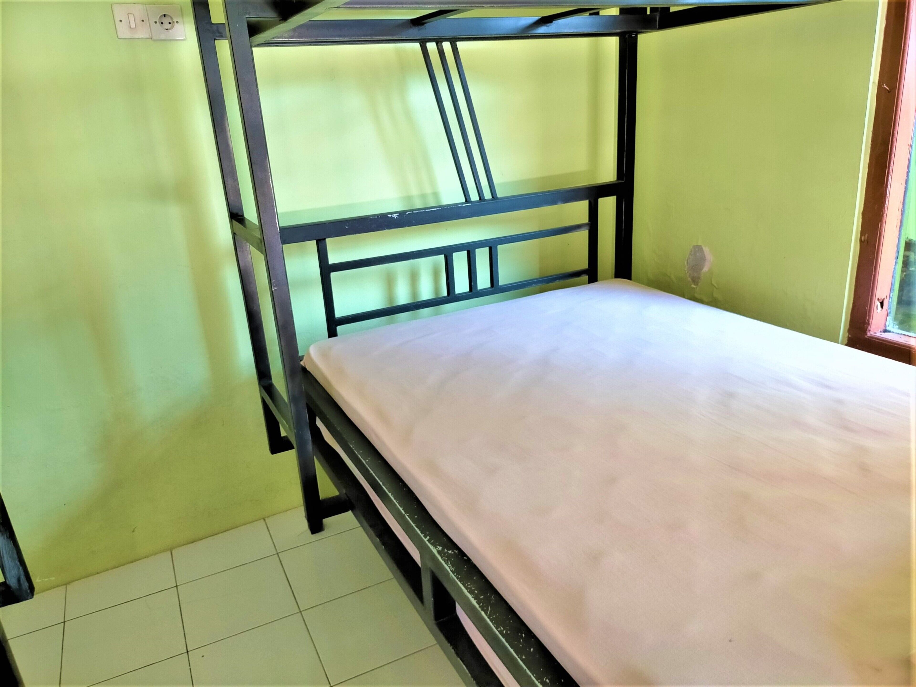 A bunk bed with a mattress, metal frame, and a wall socket.