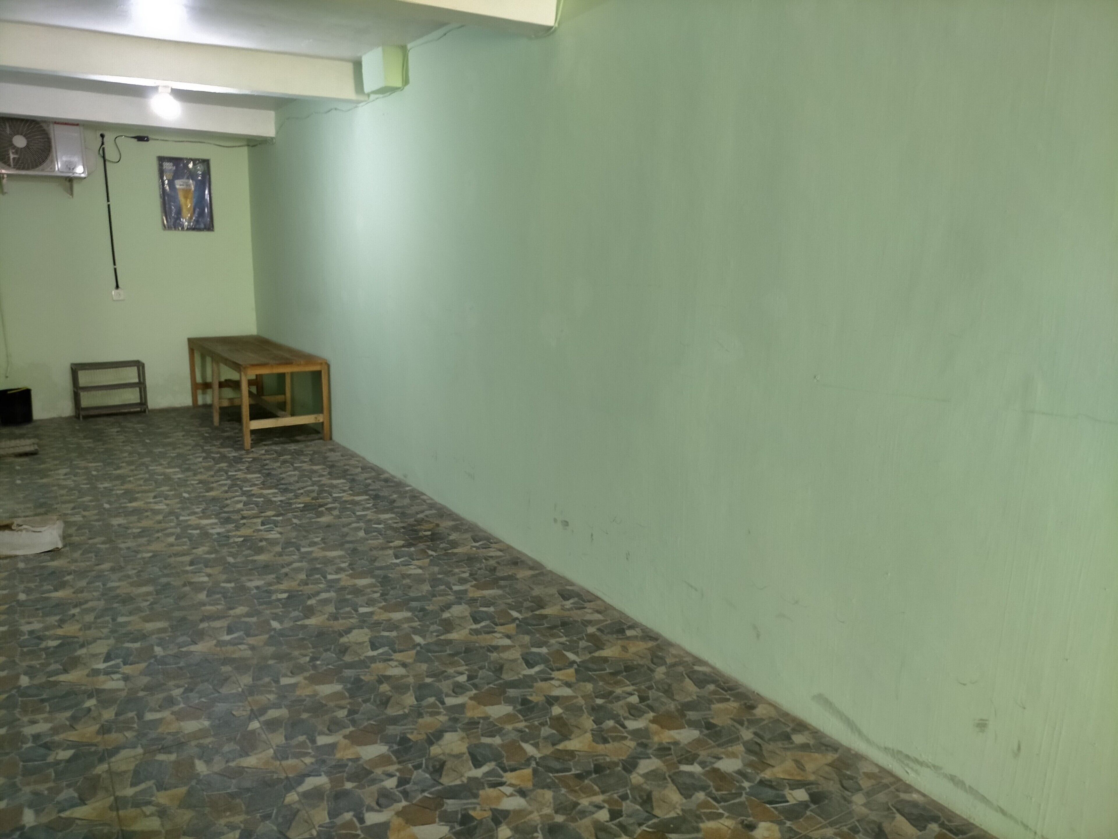 A room with a tiled floor, a wooden table, and a wall-mounted air conditioning unit.