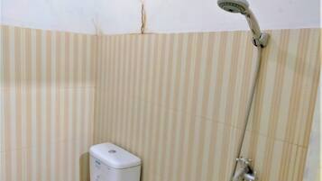A bathroom with striped beige tiles, a handheld showerhead, and a white soap dispenser.