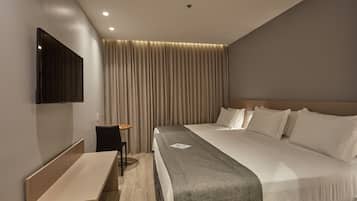 Une chambre d’hôtel moderne dotée d’un grand lit, d’un téléviseur à écran plat fixé au mur, d’un bureau et d’une chaise.