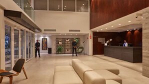 A spacious lobby with a reception desk, seating area, and glass doors leading to other rooms. - Flix Hotel (Maceió)