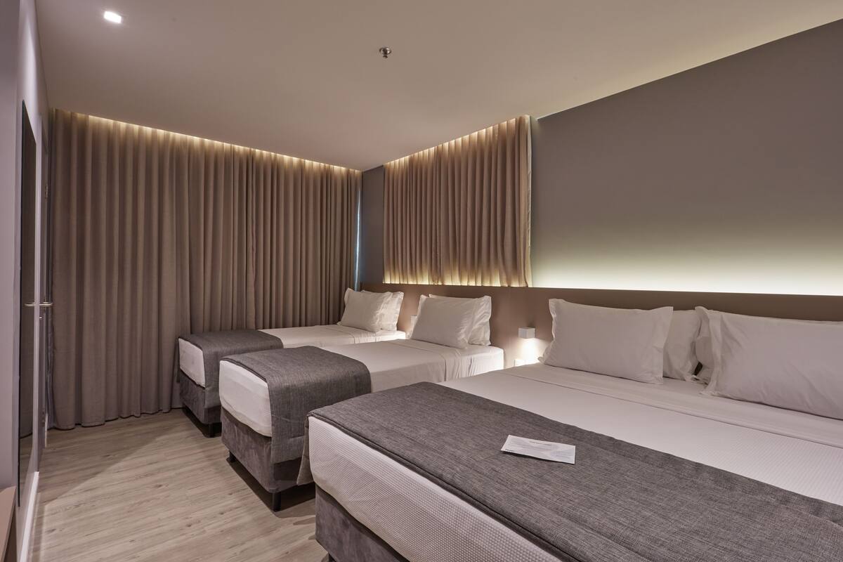 Una habitación de hotel moderna con dos camas individuales, un espejo grande y piso de madera.