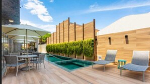 An outdoor patio with a pool, lounge chairs, and a wooden wall with greenery. - Flix Hotel (Maceió)
