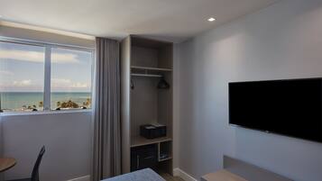 Habitación de hotel con cama, televisión, escritorio y ventana con vista a la playa.