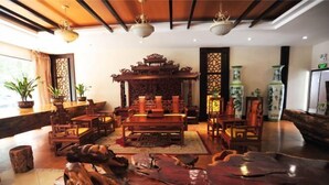 Una habitación de estilo tradicional con muebles de madera, una mesa central ornamentada y jarrones decorativos.