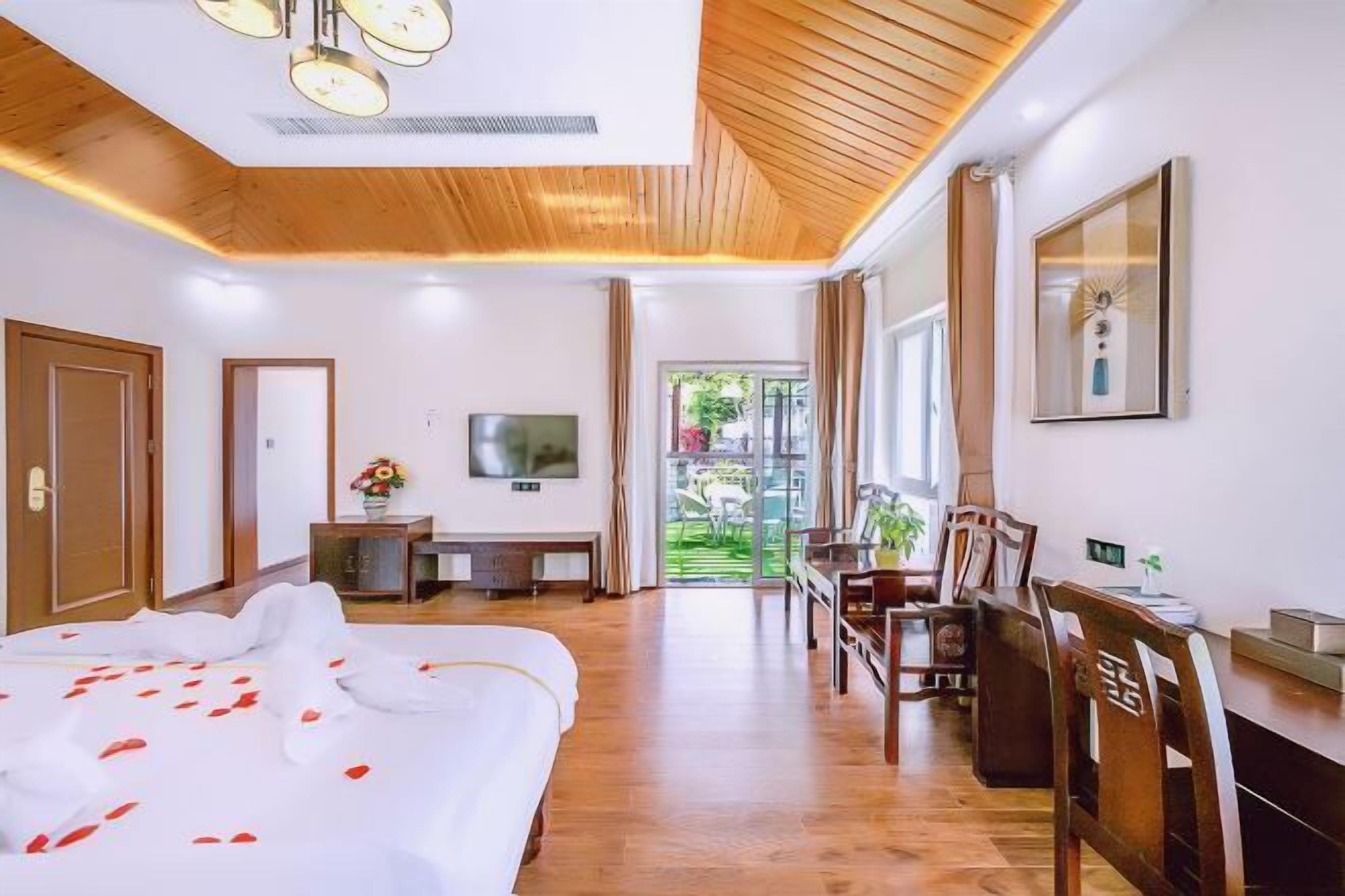 Habitación de hotel con cama, escritorio, televisor y vistas al exterior.