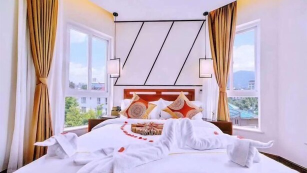 Una cama bien hecha con sábanas blancas, cabecera de madera y almohadas decorativas.