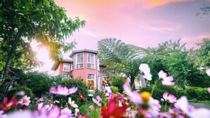 Una casa rosa rodeada de exuberante follaje y flores.