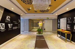 Un vestíbulo de hotel con mostrador de recepción, un banco y una pared con texto y gráficos.