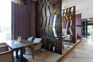 Un comedor moderno con mesa de vidrio, sillas acolchadas y una pared decorativa.