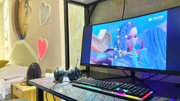 A gaming setup with a monitor, keyboard, and headphones on a desk.