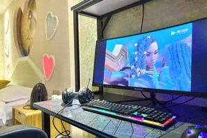 A gaming setup with a monitor, keyboard, and headphones on a desk. - Haoyi Hotel (Zhuzhou)
