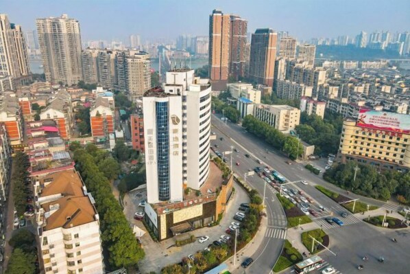 A high-rise building with a modern design, surrounded by a busy urban environment with other high-rise buildings and a clear sky. - Haoyi Hotel (Zhuzhou)