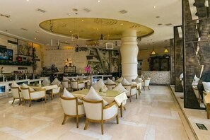 A spacious hotel lobby with multiple seating areas, a central column, and a bar area.