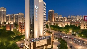 A modern hotel with a prominent vertical sign, surrounded by a cityscape with multiple high-rise buildings. - Haoyi Hotel (Zhuzhou)
