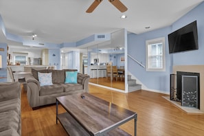 Relax in this stylish living space with a sofa, TV, and wooden staircase leading to an upper level.