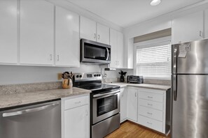 Enjoy cooking in this well-equipped kitchen with stainless steel appliances, white cabinetry, and granite countertops.