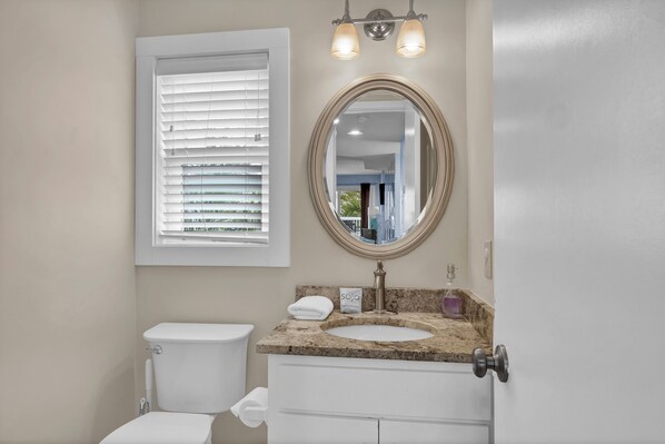 A bathroom with a toilet, sink, vanity, and a window with blinds. - Wonderful Ocean View Condo on Wrightsville Beach (Wrightsville Beach)