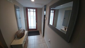 A narrow hallway with a door at the end, a basket on a counter, and a large mirror on the right wall. - Studio - A short walk everywhere - Great Fall and Spring Rates (Ogunquit)