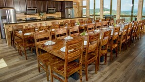 A spacious wooden dining area with a large island, equipped with modern appliances and surrounded by large windows offering scenic views.