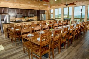 Un comedor espacioso de madera con una isla grande, equipado con electrodomésticos modernos y rodeado de amplios ventanales con vistas panorámicas.