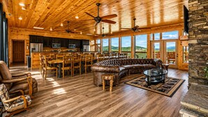 A spacious living area with a wooden ceiling, leather sofa, dining table, and chairs.