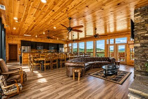 A spacious living area with a wooden ceiling, leather sofa, dining table, and chairs.