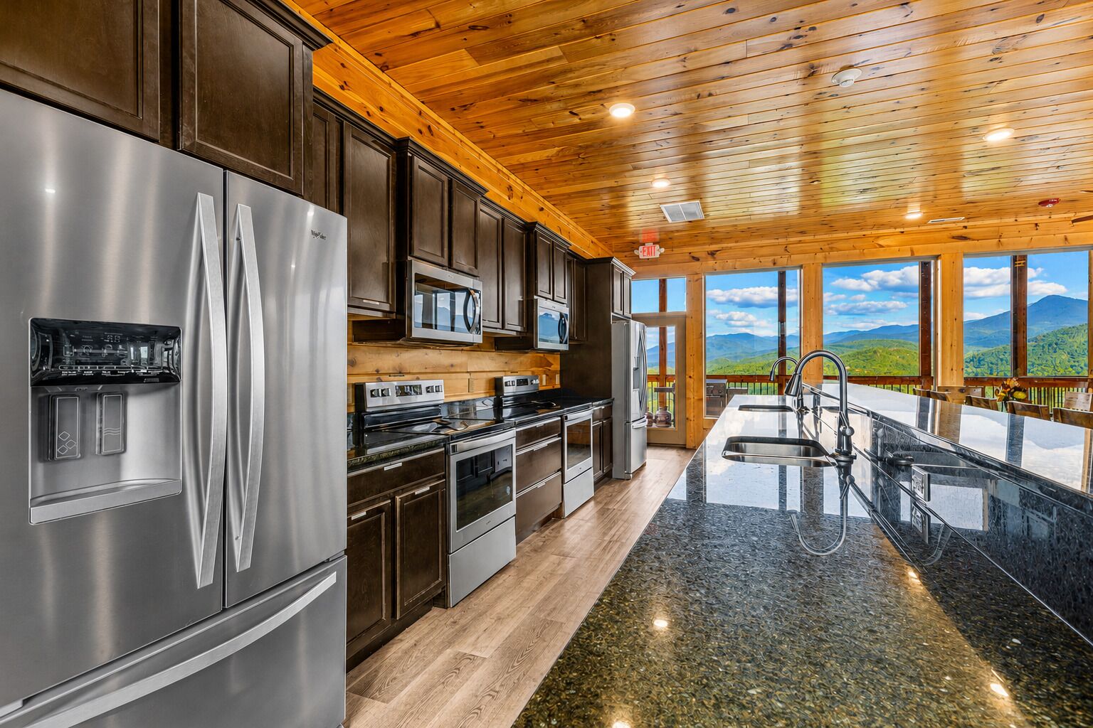 A modern kitchen with stainless steel appliances, wooden cabinets, and a large island with a sink.