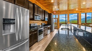 A modern kitchen with stainless steel appliances, wooden cabinets, and a large island with a sink.
