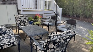 Una terraza con mobiliario exterior, incluyendo sillas y una mesa, y una escalera que conduce a otra terraza.