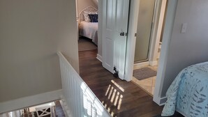 A staircase leading to a bedroom with a bed, a door, and a small rug. - Cozy Cottage at Footbridge Beach - Great Fall and Spring Rates (Ogunquit)