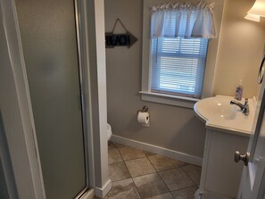 A bathroom with a toilet, sink, and window with blinds. - Cozy Cottage at Footbridge Beach - Great Fall and Spring Rates (Ogunquit)