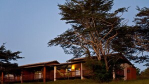 A two-story lodge with a porch and a large tree in front. - Rio das Garças Eco Resort (Sao Jose de Mipibu)
