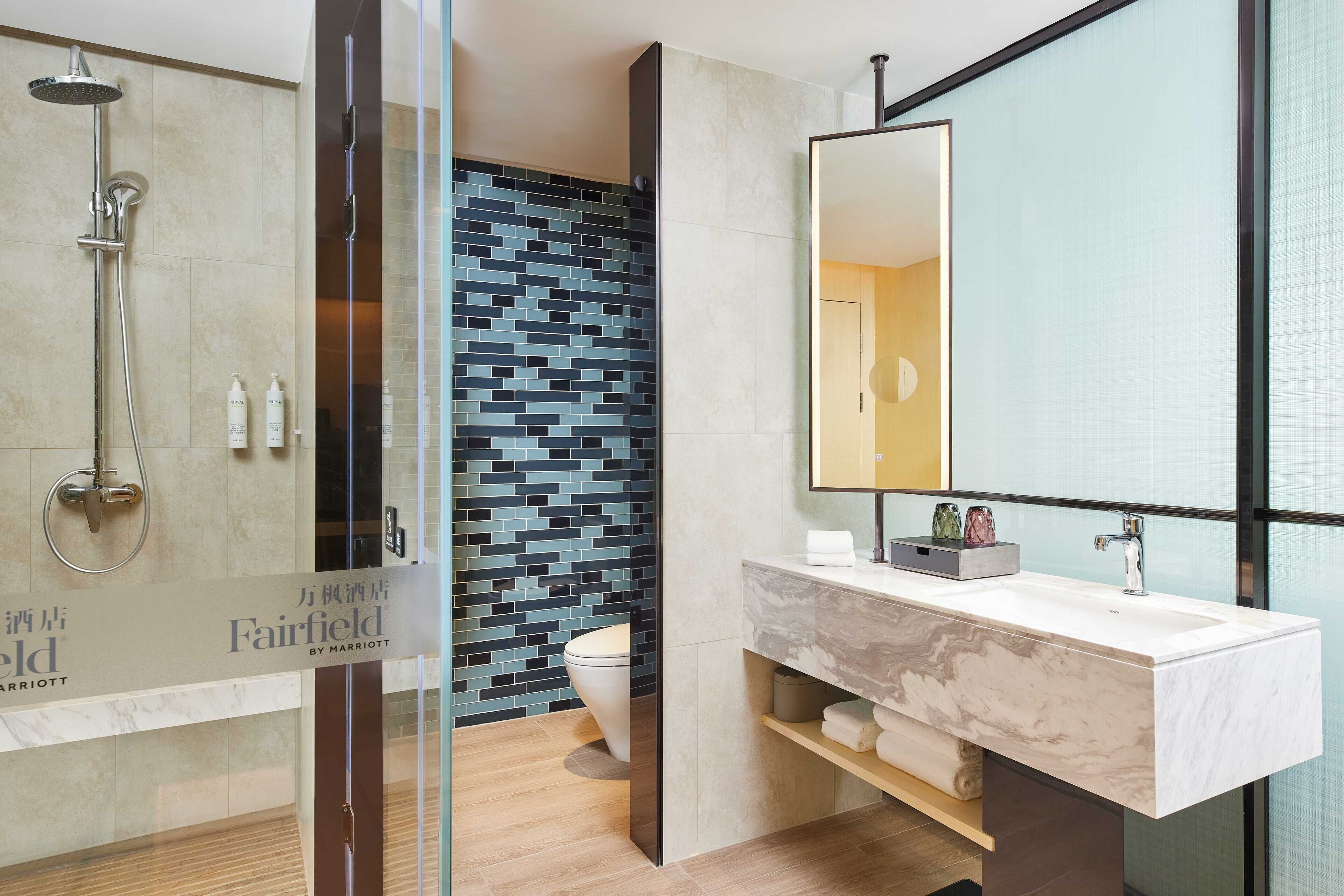 A modern bathroom with a glass shower enclosure, a marble sink, and a tiled backsplash.