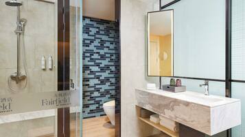 A modern bathroom with a glass shower enclosure, a marble sink, and a tiled backsplash.