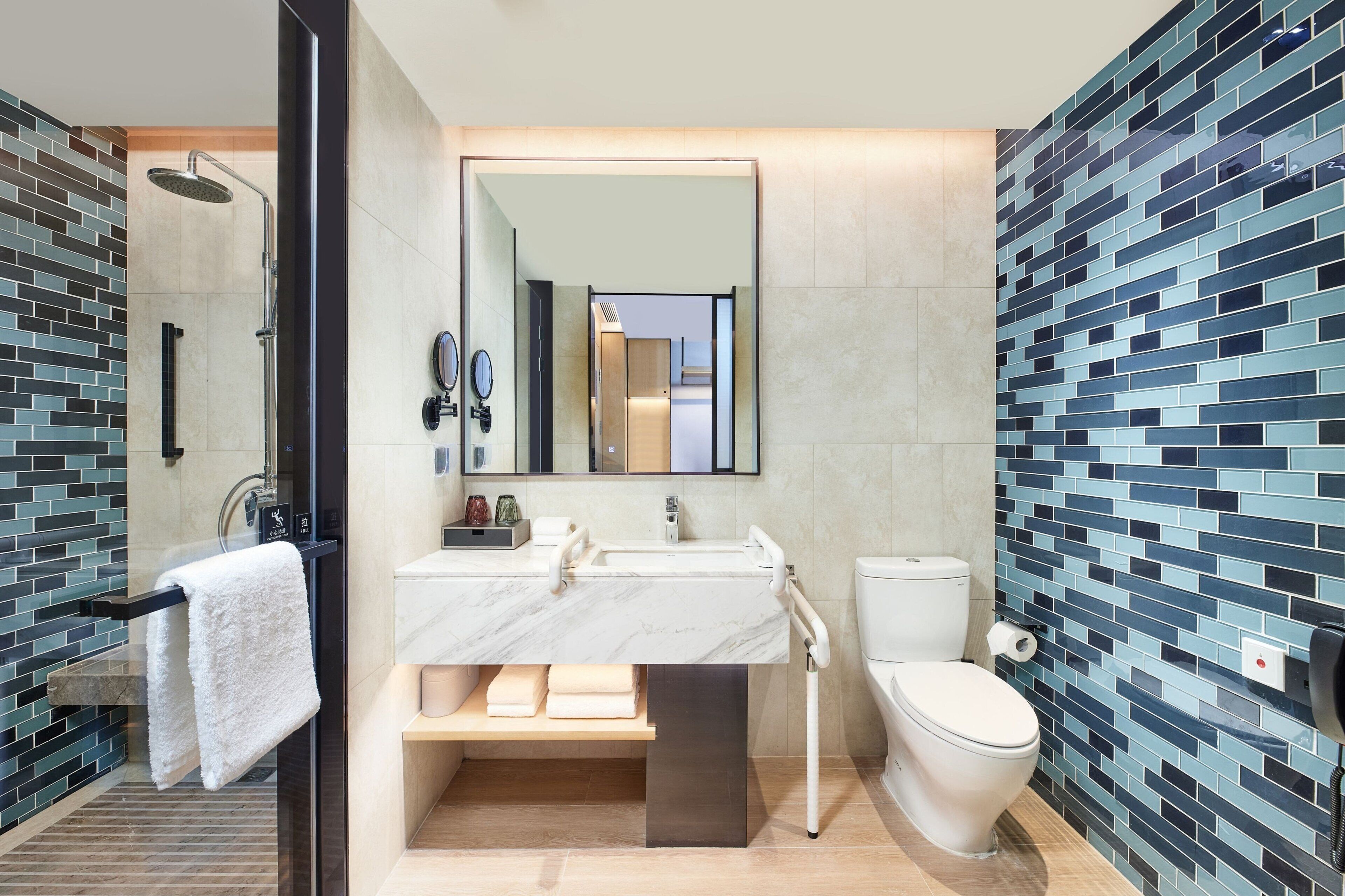 A modern bathroom with a glass-enclosed shower, a marble sink, and a toilet.