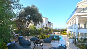 A poolside area with outdoor seating and a view of a building. - 5 bedroom luxury villa with private pool and garden in oludeniz (Fethiye)