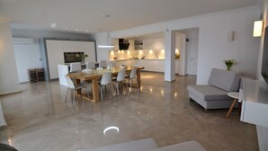 A spacious living area with a dining table and chairs, a grey sofa, and a kitchen in the background. - 5 bedroom luxury villa with private pool and garden in oludeniz (Fethiye)