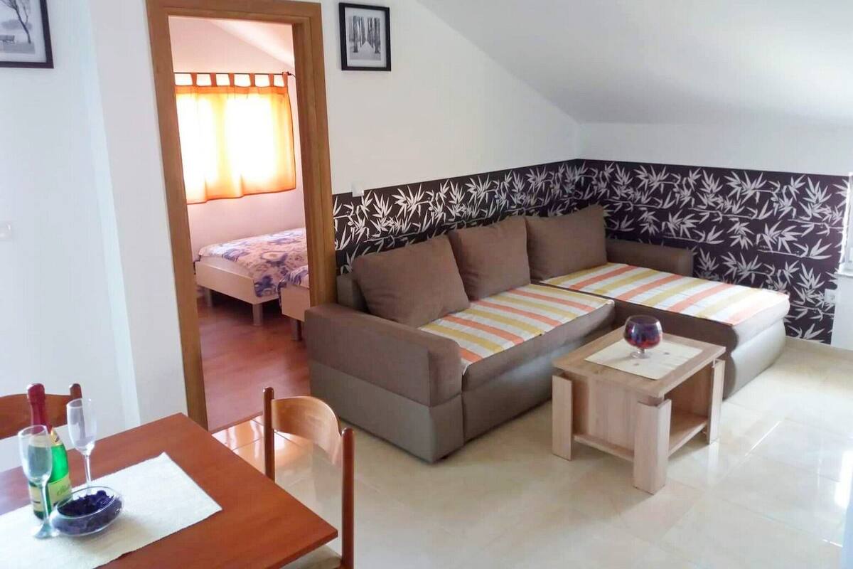 A small, cozy room with a sofa, a dining table, and a bed with a curtain.