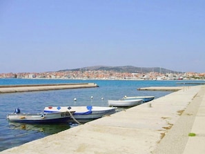 A marina with boats docked, a clear sky, and a distant cityscape. - Apartments Kristina (Vodice)