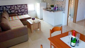 Un espacio habitable compacto con kitchenette, un sofá, una pequeña mesa de comedor y una silla.